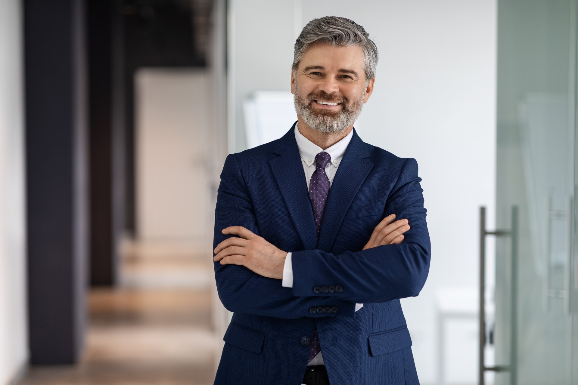 Portrait Of Handsome Middle Aged Businessman In Suit Standing With Folded Arms